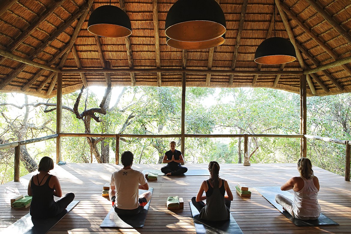 People doing yoga on the The Londolozi Yoga Deck